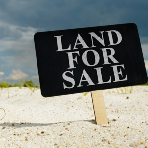 Sign in the sand saying "Land for Sale"